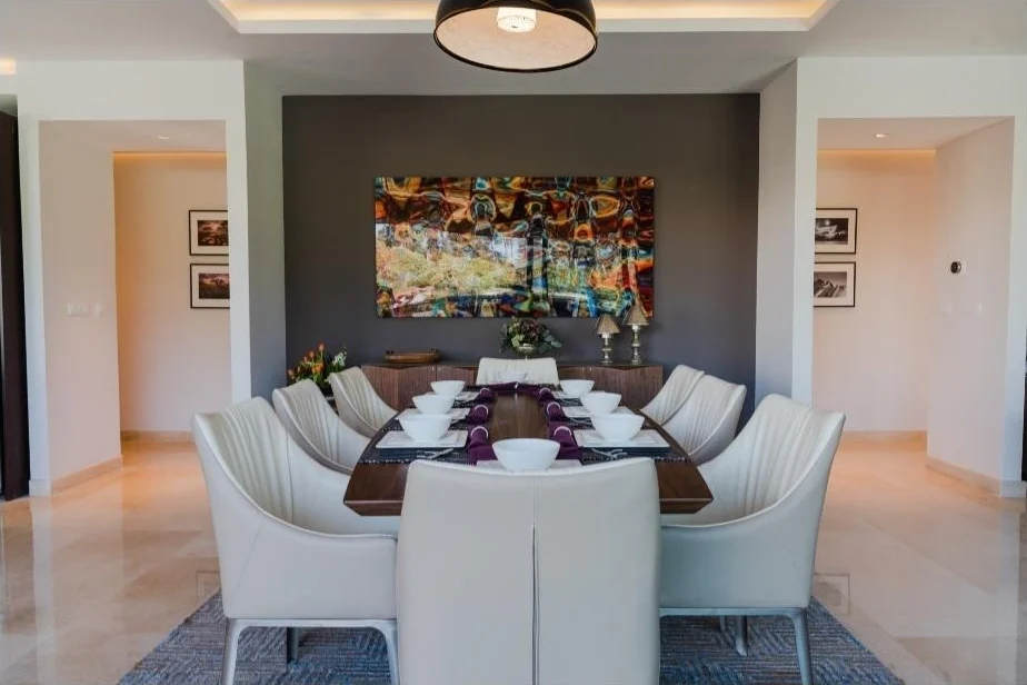 Comedor formal para ocho personas con muro gris oscuro y obra de arte a color