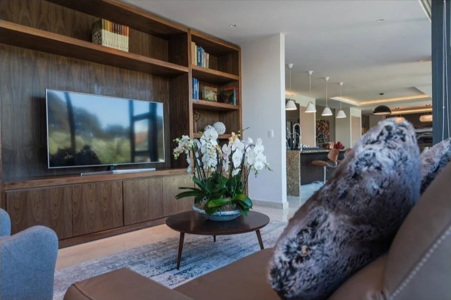 Sala de televisión con librero de nogal y orquídeas