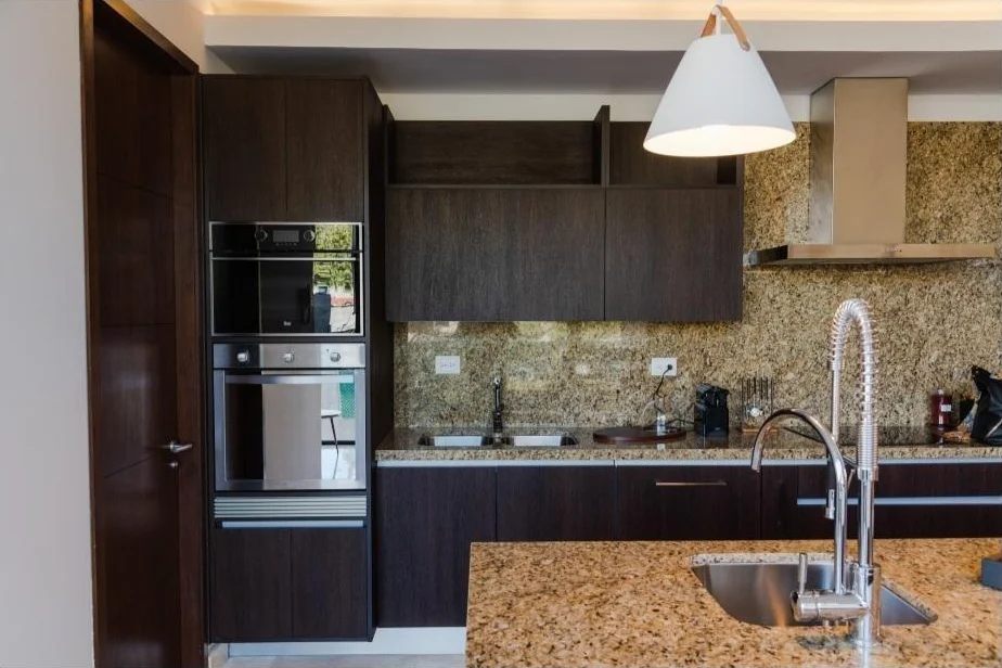 Cocina con hornos empotrados, campana y barra de granito